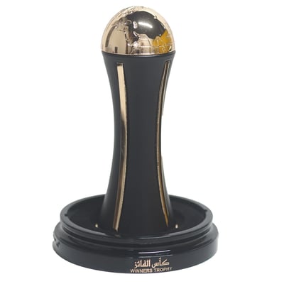 Lattafa Pride Al Khas Winners Trophy Gold 100ml — A black perfume box with gold Arabic and English text, and a gold-capped black perfume bottle shaped like an hourglass, displayed on a white background. | Lattafa Pride Al Khas Winners Trophy Gold 100ml — Kotak minyak wangi hitam dengan teks Arab dan Inggeris emas, dan