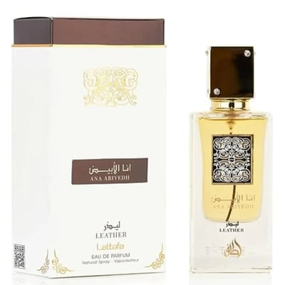 Lattafa Ana Abiyedh Leather 60ml by Lattafa Perfumes — A white perfume box with gold Arabic calligraphy and a clear glass bottle with gold accents and a dark brown cap, displayed side-by-side. | Lattafa Ana Abiyedh Leather 60ml by Lattafa Perfumes — Kotak minyak wangi putih dengan kaligrafi Arab emas dan botol kaca