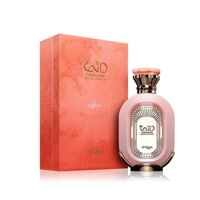Zimaya Daiman Eden Eau De Parfum 100ml by Zimaya — A pink textured perfume bottle with gold accents stands next to its matching coral-orange textured box with gold marbling. | Zimaya Daiman Eden Eau De Parfum 100ml by Zimaya — Sebotol minyak wangi merah jambu bertekstur dengan perincian emas berdiri di sebelah kotak