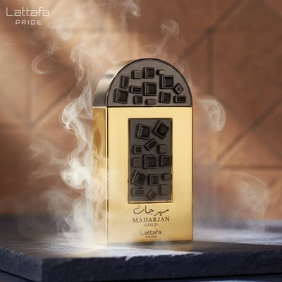 Lattafa Pride Maharjan Gold — A gold perfume bottle with a black and gold mosaic cap sits next to its matching ornate dark green box, both on a white background. | Lattafa Pride Maharjan Gold — Botol minyak wangi emas dengan penutup mozek hitam dan emas duduk di sebelah kotaknya yang berhias hijau gelap, kedua-duanya