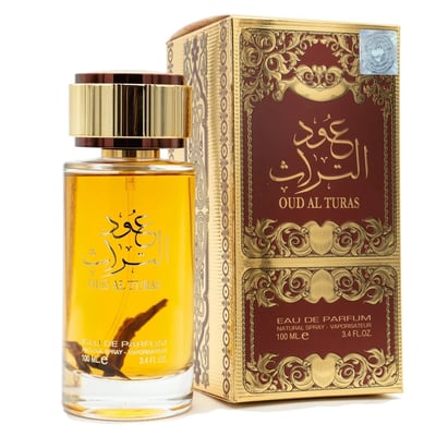 Ard Al Zaafaran Oud Al Turas — A clear glass perfume bottle with golden cap and a dark dried plant inside, next to a gold and maroon ornate box. | Botol minyak wangi kaca jernih dengan penutup emas dan tumbuhan kering gelap di dalamnya, bersebelahan dengan kotak berhias emas dan merah marun.