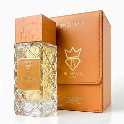Bujairami Too Damn Good — Clear faceted glass perfume bottle with wooden cap next to orange leather box with gold logo
