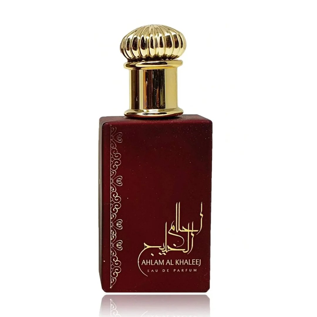 Ard Al Zaafaran Ahlam Al Khaleej 80ml by Ard Al Zaafaran — A red perfume box with gold intricate patterns and a matching red perfume bottle with a gold cap, displayed side-by-side on a white reflective surface. | Ard Al Zaafaran Ahlam Al Khaleej 80ml by Ard Al Zaafaran — Kotak minyak wangi merah dengan corak emas yang