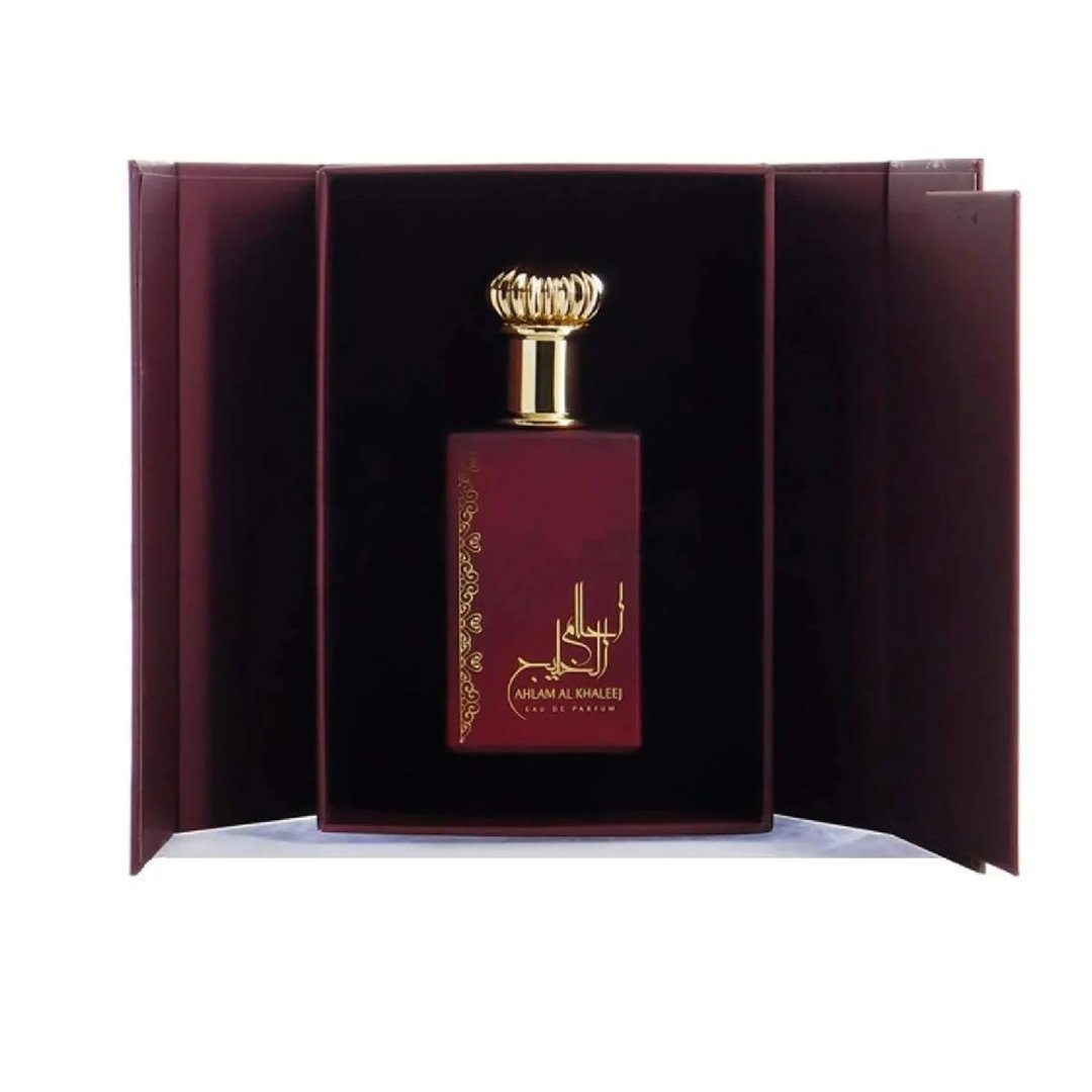 Ard Al Zaafaran Ahlam Al Khaleej 80ml by Ard Al Zaafaran — A red perfume box with gold intricate patterns and a matching red perfume bottle with a gold cap, displayed side-by-side on a white reflective surface. | Ard Al Zaafaran Ahlam Al Khaleej 80ml by Ard Al Zaafaran — Kotak minyak wangi merah dengan corak emas yang