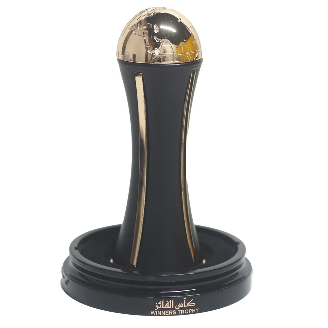 Lattafa Pride Al Khas Winners Trophy Gold 100ml — A black perfume box with gold Arabic and English text, and a gold-capped black perfume bottle shaped like an hourglass, displayed on a white background. | Lattafa Pride Al Khas Winners Trophy Gold 100ml — Kotak minyak wangi hitam dengan teks Arab dan Inggeris emas, dan