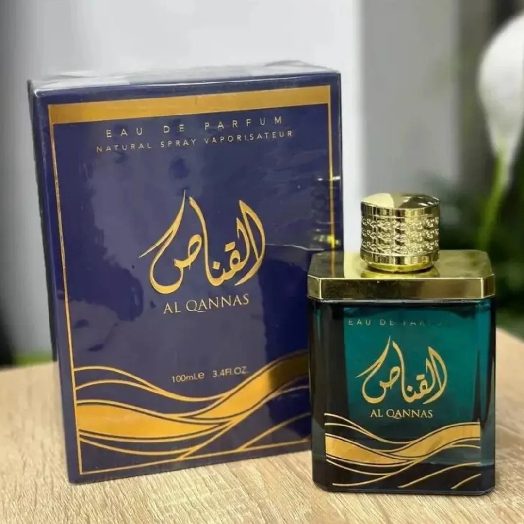 Ard Al Zaafaran Al Qannas Eau De Parfum 100ml — A blue perfume bottle and its matching blue box with gold Arabic calligraphy and wavy lines, displayed side-by-side on a white background. | Ard Al Zaafaran Al Qannas Eau De Parfum 100ml — Botol minyak wangi biru dan kotak birunya yang sepadan dengan kaligrafi Arab emas