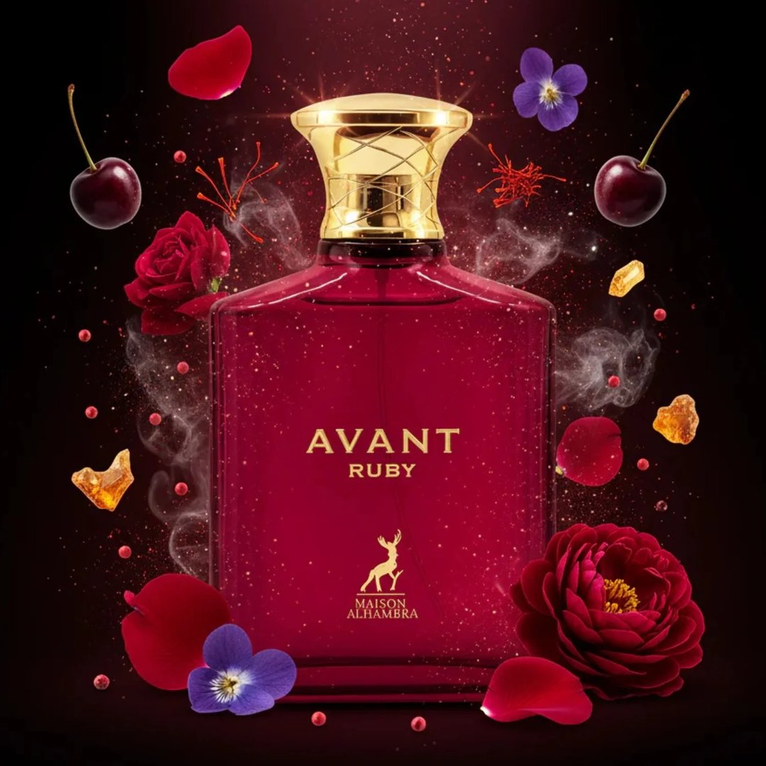 Maison Alhambra Avant Ruby Eau De Parfum 100ml — A bright pink glass perfume bottle with a gold textured cap stands next to its white and gold patterned box, both featuring the Avant Ruby branding and a deer logo. | Maison Alhambra Avant Ruby Eau De Parfum 100ml — Botol kaca berwarna merah jambu terang dengan penutup
