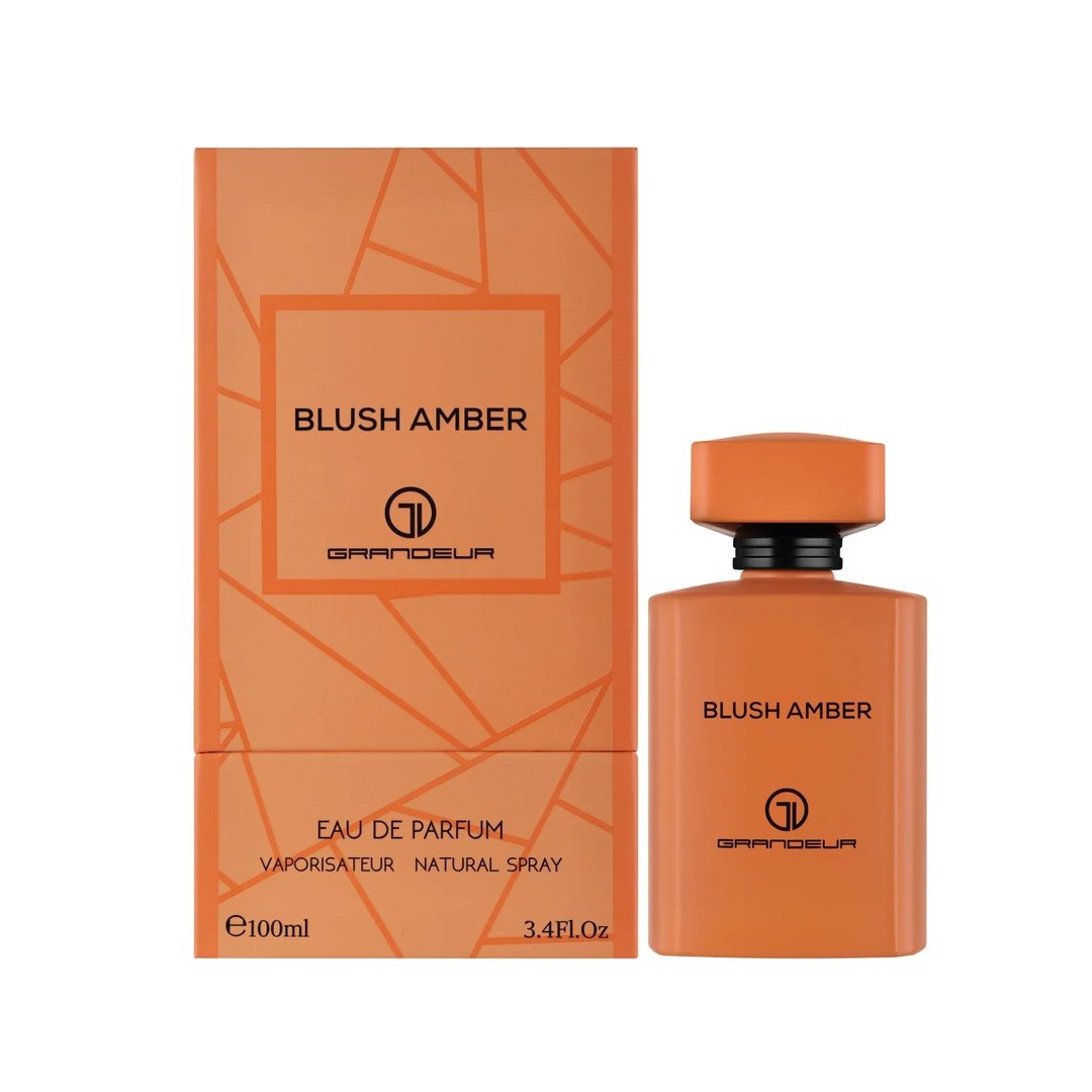 Grandeur Blush Amber 100ml — An orange perfume bottle and its matching orange box with geometric patterns, displayed side-by-side against a white background. | Grandeur Blush Amber 100ml — Botol minyak wangi oren dan kotak orennya yang sepadan dengan corak geometri, dipaparkan bersebelahan di atas latar belakang putih.