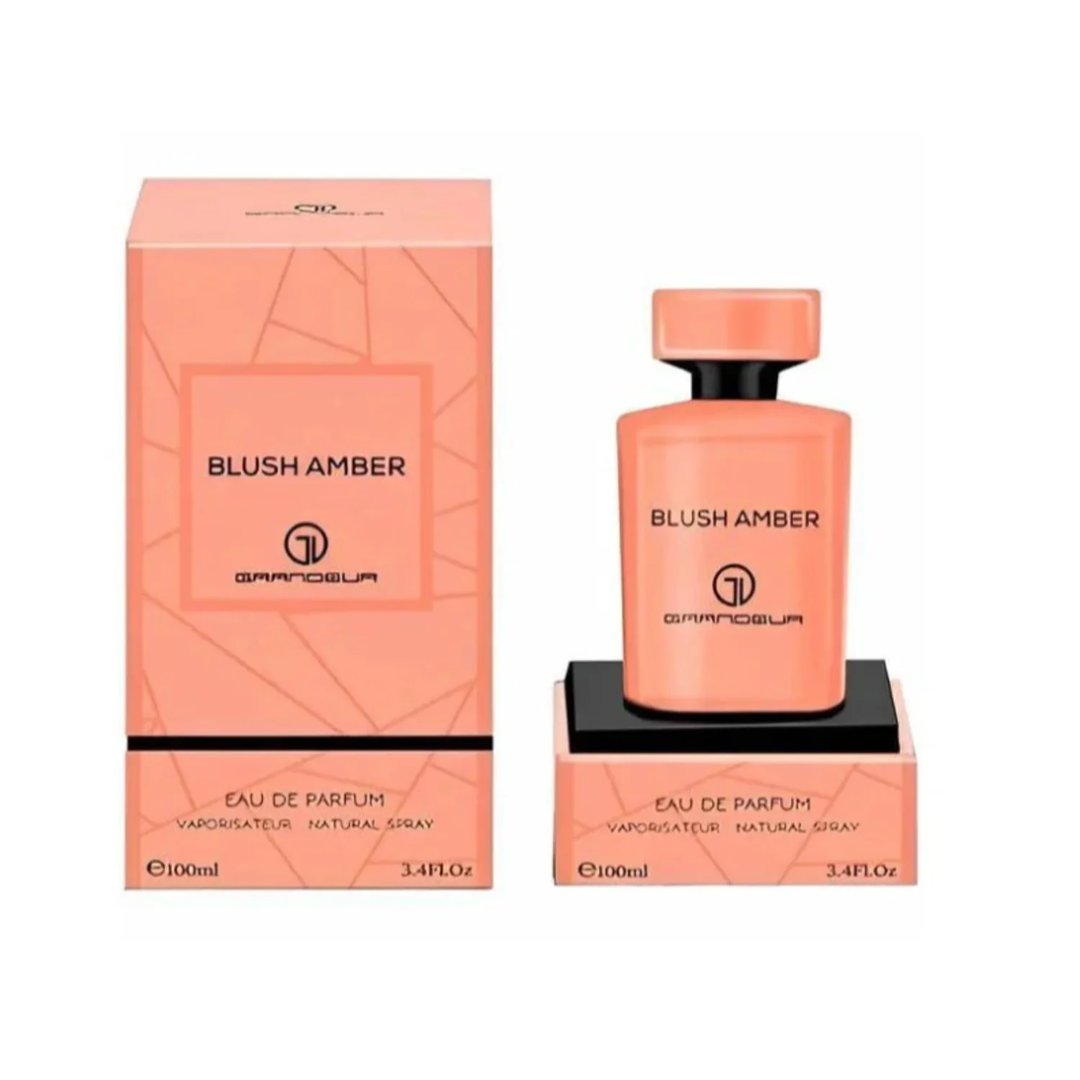 Grandeur Blush Amber 100ml — An orange perfume bottle and its matching orange box with geometric patterns, displayed side-by-side against a white background. | Grandeur Blush Amber 100ml — Botol minyak wangi oren dan kotak orennya yang sepadan dengan corak geometri, dipaparkan bersebelahan di atas latar belakang putih.
