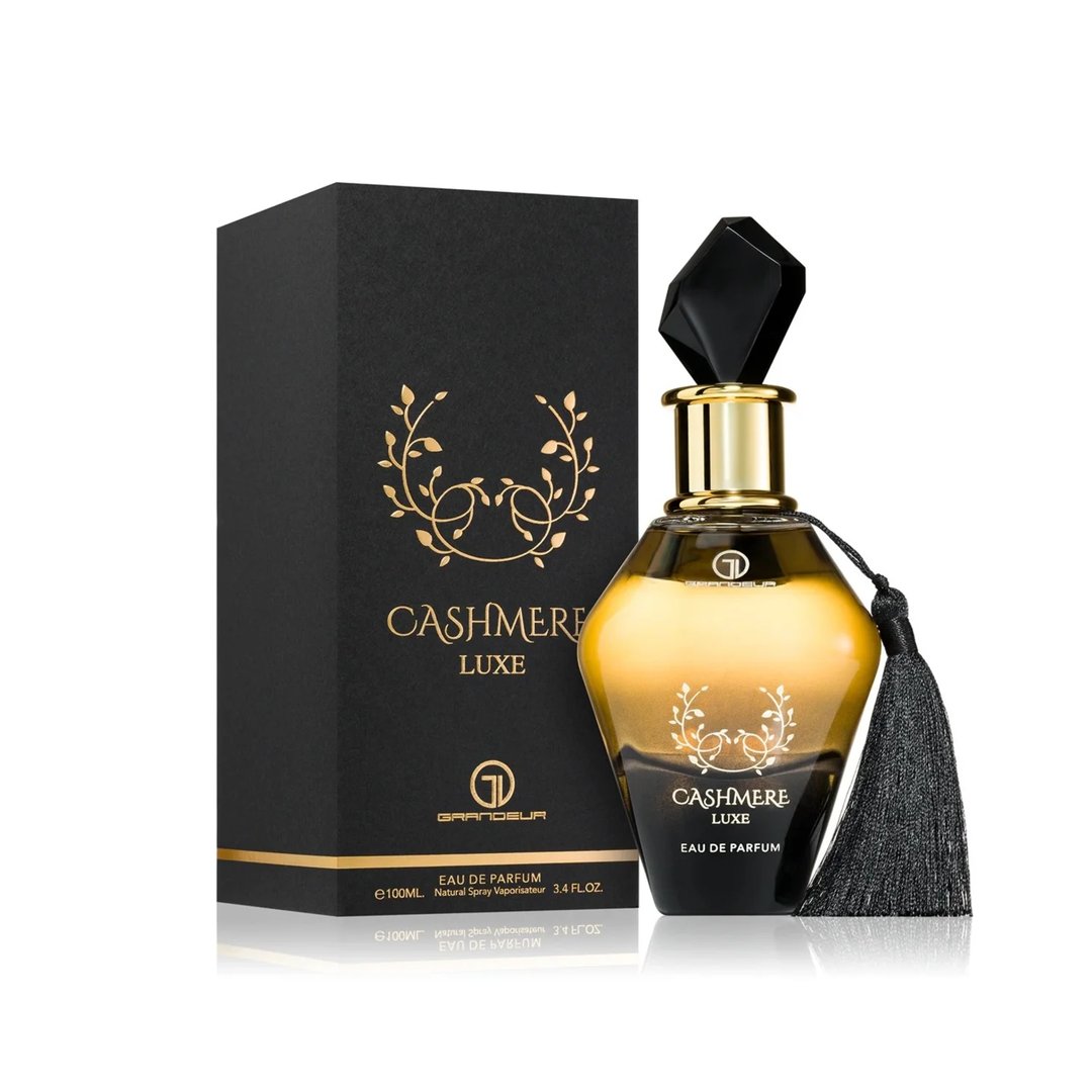 Grandeur Cashmere Luxe 100ml by Grandeur — A faceted glass perfume bottle with a black gem-like cap and a black tassel hanging from the neck, against a white background. | Grandeur Cashmere Luxe 100ml by Grandeur — Botol kaca berfaset dengan penutup seperti permata hitam dan juntai hitam tergantung di lehernya