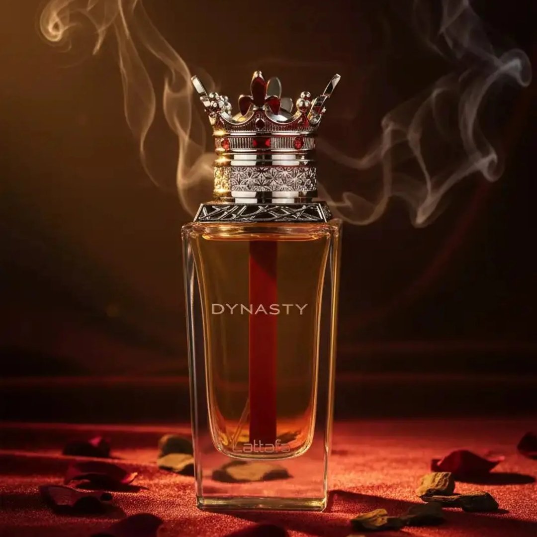Lattafa Dynasty Lattafa 100ml EDP Unisex — A maroon textured box with a white ornate crest sits next to a clear glass perfume bottle topped with a silver crown-shaped cap with red accents.