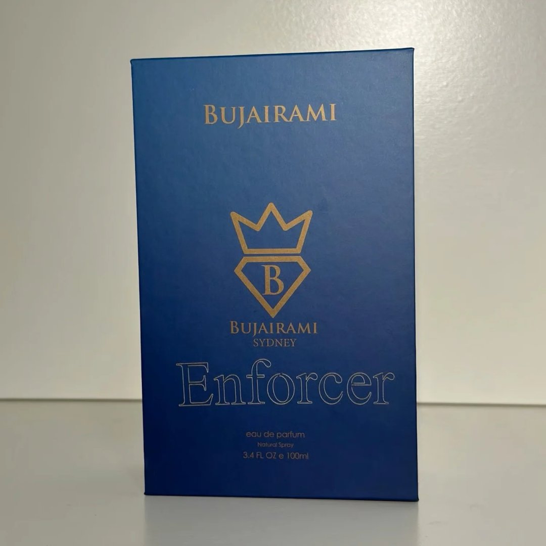 Bujairami Enforcer Eau de Parfum — Blue faceted glass bottle with gold cap next to blue box with gold logo