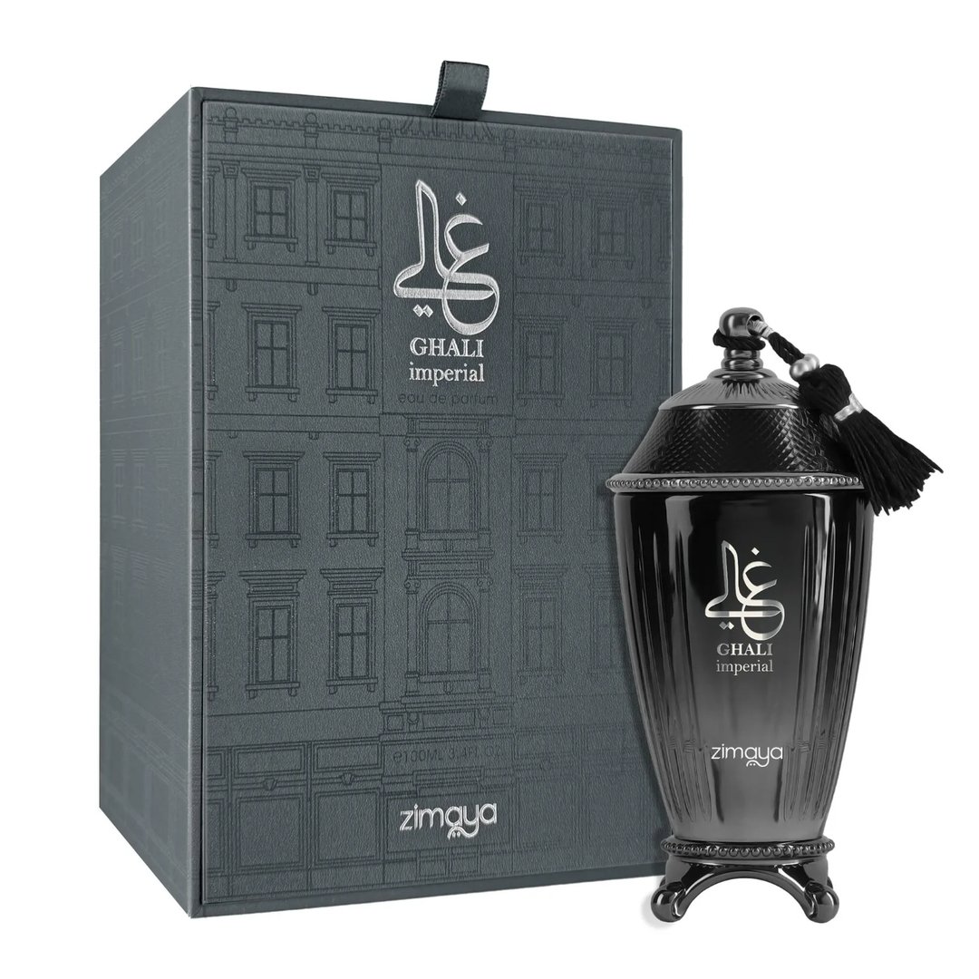 Zimaya Ghali Imperial Eau De Parfum — A dark grey textured box with a building facade pattern stands next to a dark, fluted perfume bottle with a tassel. | Zimaya Ghali Imperial Eau De Parfum — Kotak kelabu gelap bertekstur dengan corak fasad bangunan berdiri di sebelah botol minyak wangi gelap berlekuk dengan juntai.