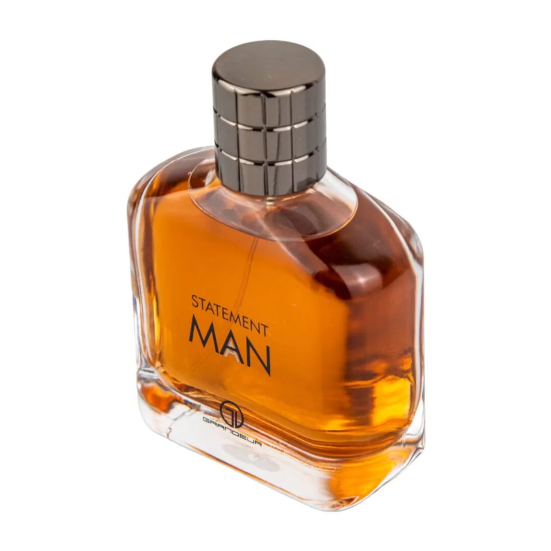 Grandeur Statement Man Eau De Parfum 100ml — A clear glass perfume bottle with amber liquid, a silver ribbed cap, and black text reading 'STATEMENT MAN' and a logo | Grandeur Statement Man Eau De Parfum 100ml — Botol minyak wangi kaca jernih dengan cecair berwarna ambar, penutup perak berjalur, dan teks hitam bertulis