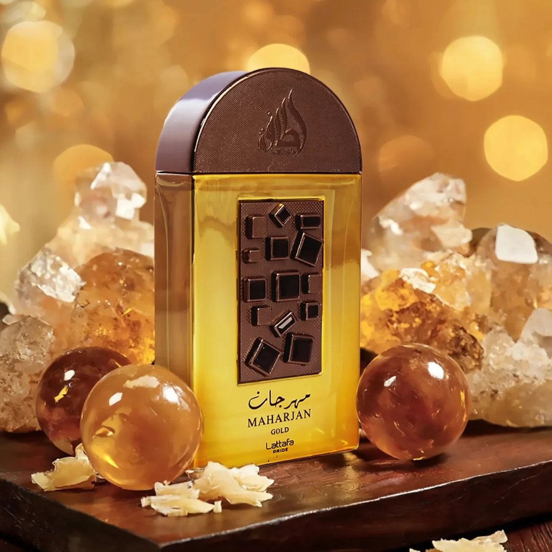 Lattafa Pride Maharjan Gold — A gold perfume bottle with a black and gold mosaic cap sits next to its matching ornate dark green box, both on a white background. | Lattafa Pride Maharjan Gold — Botol minyak wangi emas dengan penutup mozek hitam dan emas duduk di sebelah kotaknya yang berhias hijau gelap, kedua-duanya