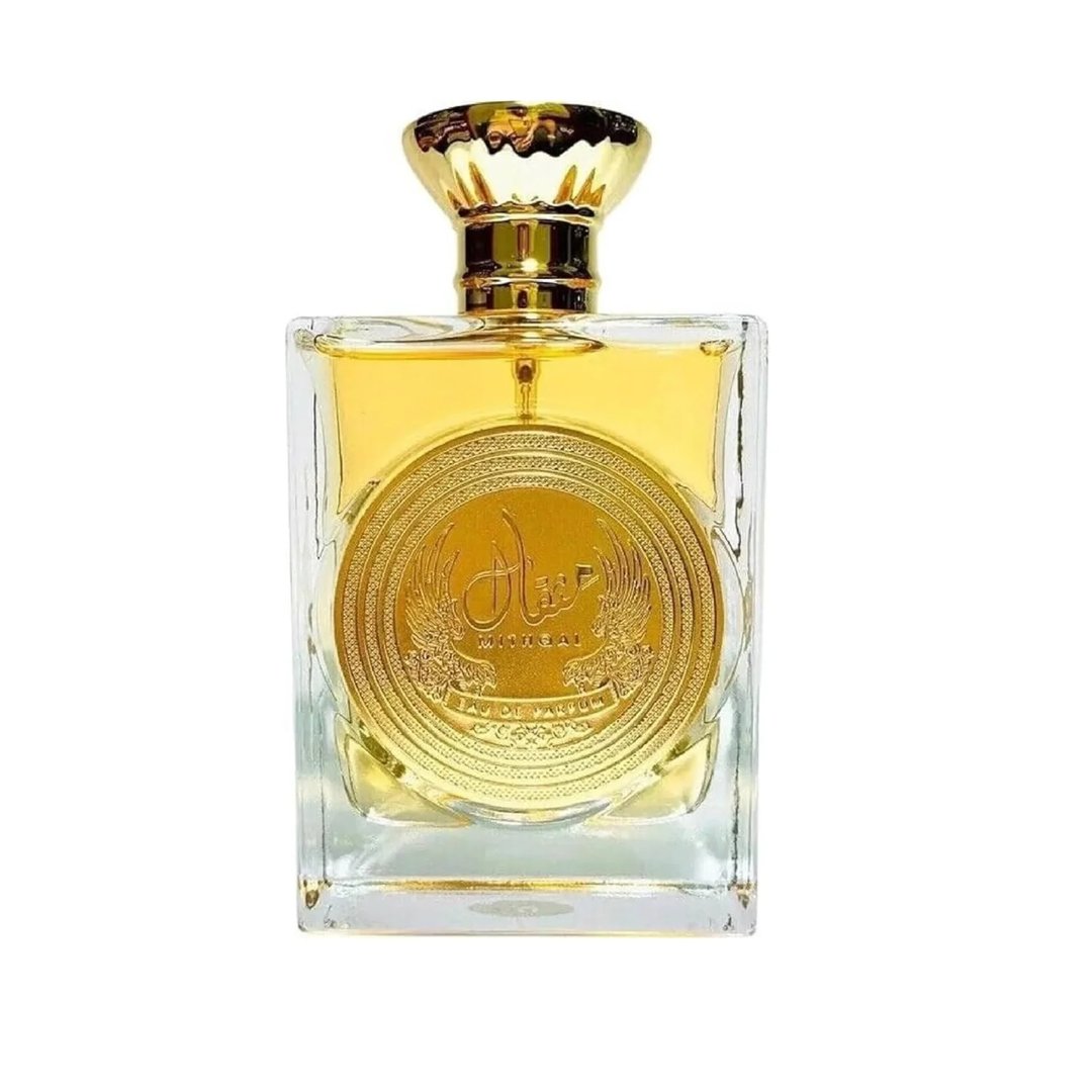 Ard Al Zaafaran Mithqal 100ml — A clear glass perfume bottle with gold liquid and a circular gold emblem, next to its white and gold patterned box with a matching emblem. | Ard Al Zaafaran Mithqal 100ml — Botol minyak wangi kaca jernih dengan cecair emas dan lambang emas bulat, bersebelahan dengan kotak corak putih