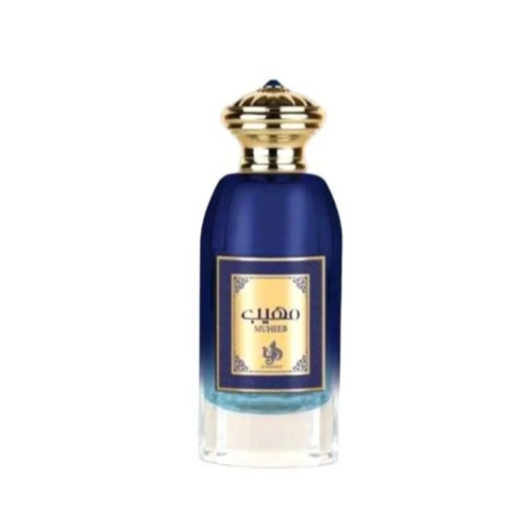 Al Wataniah Muheeb Perfume Man by Al Wataniah 100ml — A dark blue perfume bottle with a gold cap sits next to its matching dark blue box with ornate gold Arabic calligraphy and floral designs. | Al Wataniah Muheeb Perfume Man by Al Wataniah 100ml — Botol minyak wangi biru gelap dengan penutup emas terletak di sebelah