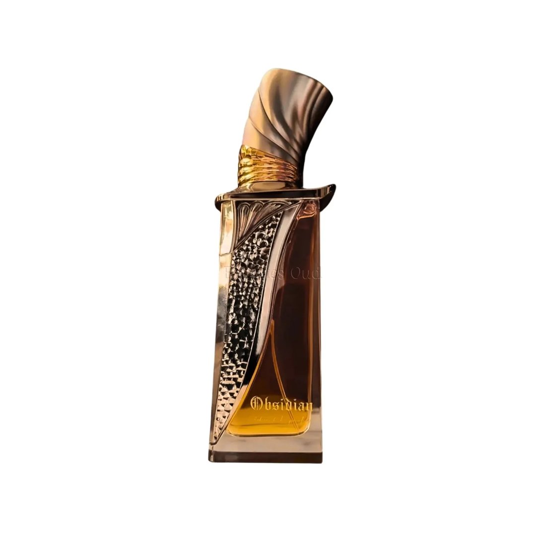 French Avenue Obsidian Eau De Parfum 100ml — A gold and black perfume bottle with ornate gold detailing stands next to its matching black box with gold artistic accents. | French Avenue Obsidian Eau De Parfum 100ml — Botol minyak wangi emas dan hitam dengan perincian emas berukir berdiri di sebelah kotak hitamnya yang