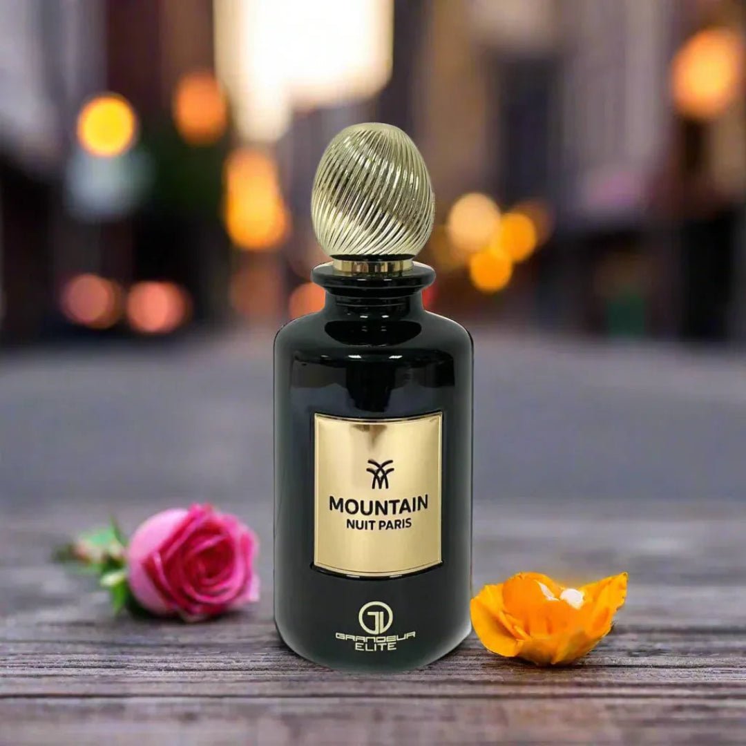 Perfume bottle labeled 'Mountain Nuit Paris' with flowers on a wooden surface