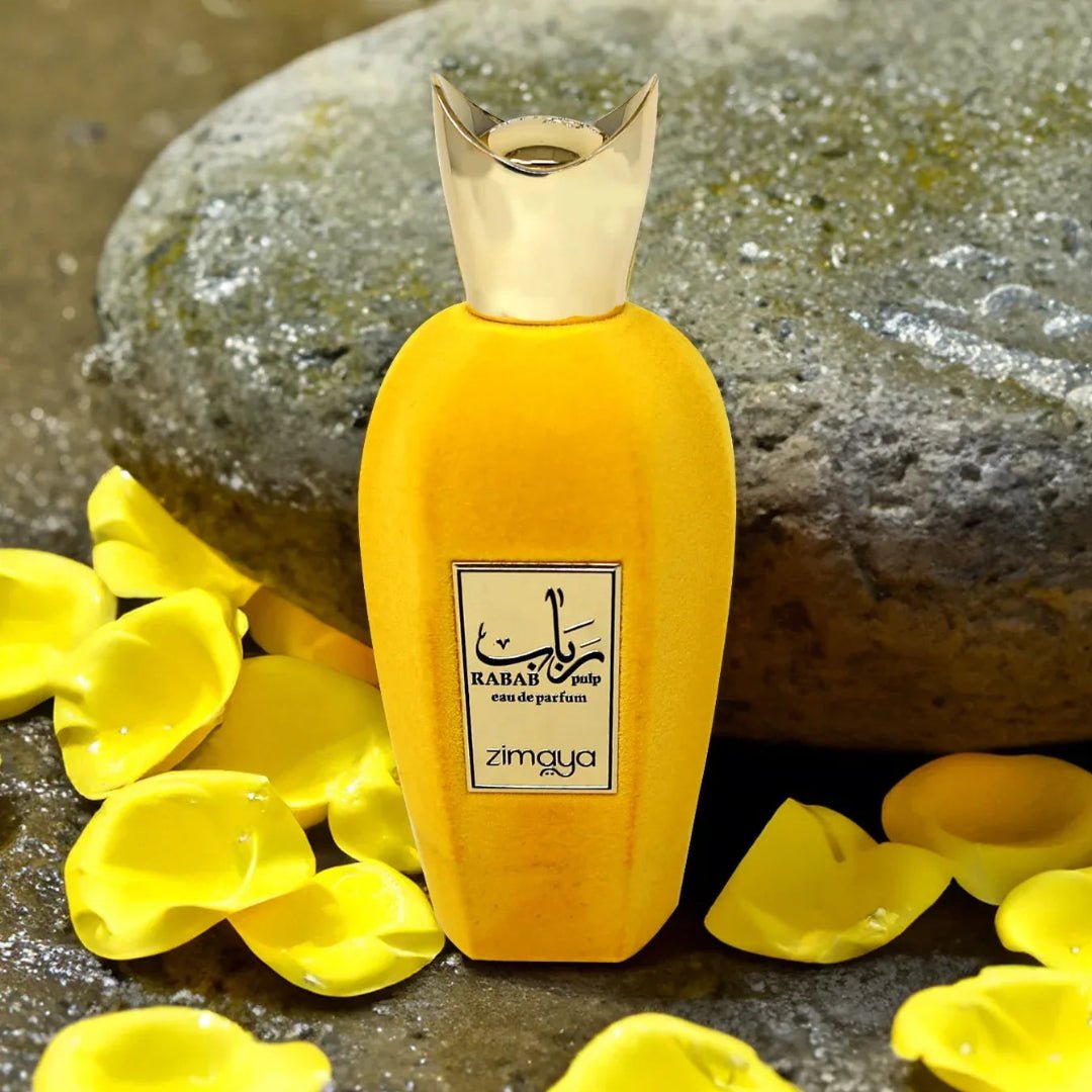 Yellow pulp perfume bottle with gold cap on a stone surface with yellow petals