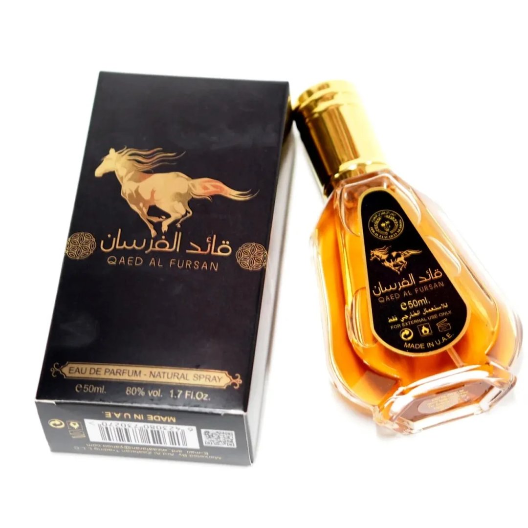 Ard Al Zaafaran Qaed Al Fursan — A gold-capped glass perfume bottle with amber liquid sits next to its black and gold box featuring a running horse graphic. | Ard Al Zaafaran Qaed Al Fursan — Botol kaca bertutup emas dengan cecair berwarna ambar duduk bersebelahan dengan kotak hitam dan emasnya yang menampilkan grafik