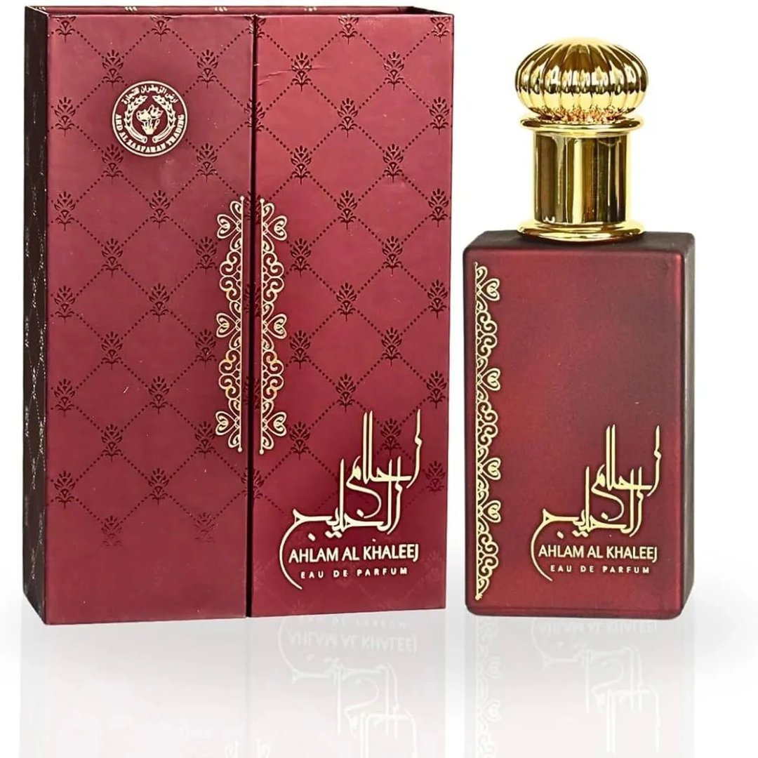 Ard Al Zaafaran Ahlam Al Khaleej 80ml by Ard Al Zaafaran — A red perfume box with gold intricate patterns and a matching red perfume bottle with a gold cap, displayed side-by-side on a white reflective surface. | Ard Al Zaafaran Ahlam Al Khaleej 80ml by Ard Al Zaafaran — Kotak minyak wangi merah dengan corak emas yang