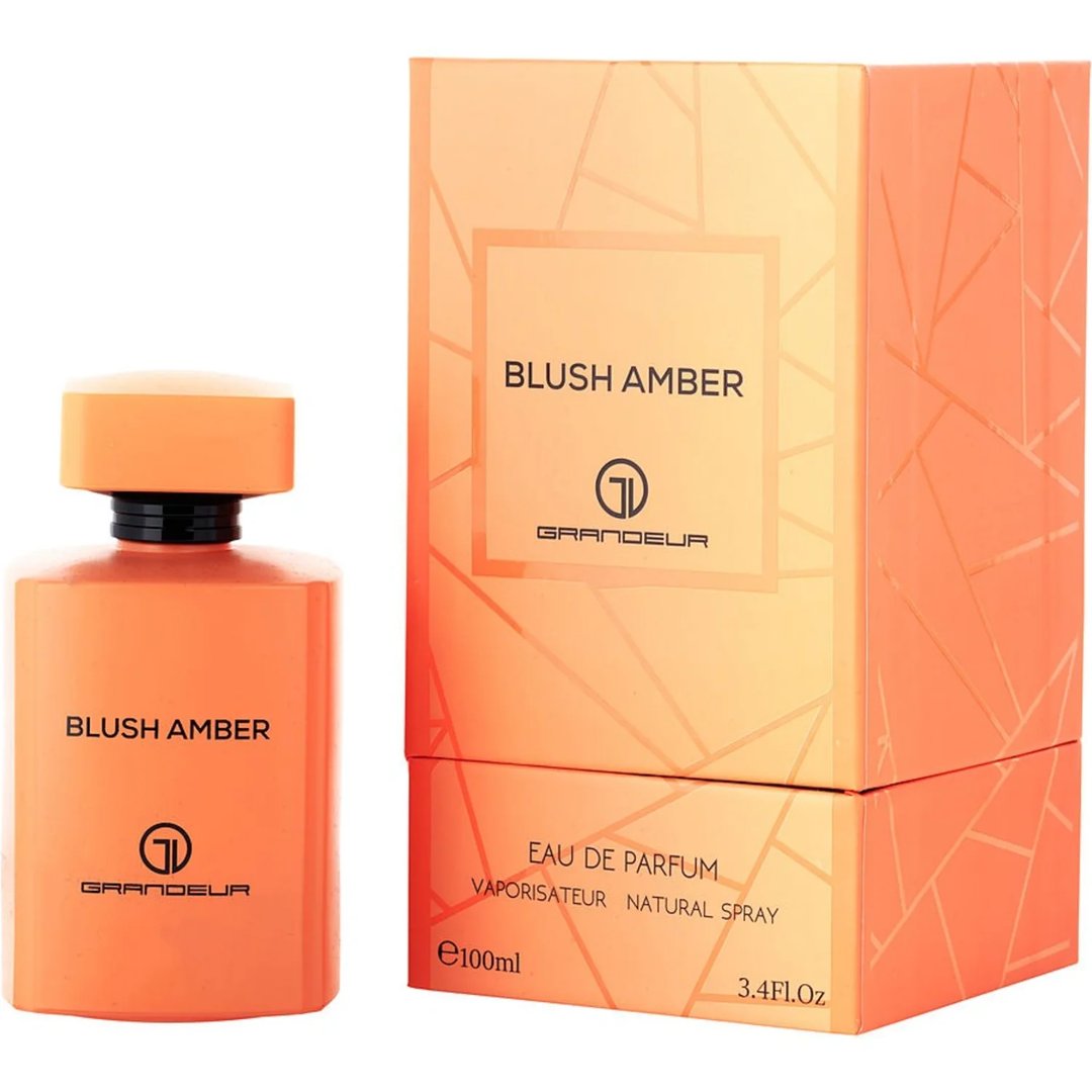 Grandeur Blush Amber 100ml — An orange perfume bottle and its matching orange box with geometric patterns, displayed side-by-side against a white background. | Grandeur Blush Amber 100ml — Botol minyak wangi oren dan kotak orennya yang sepadan dengan corak geometri, dipaparkan bersebelahan di atas latar belakang putih.