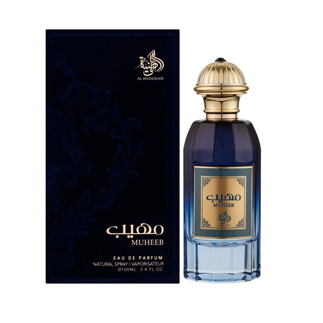 Al Wataniah Muheeb Perfume Man by Al Wataniah 100ml — A dark blue perfume bottle with a gold cap sits next to its matching dark blue box with ornate gold Arabic calligraphy and floral designs. | Al Wataniah Muheeb Perfume Man by Al Wataniah 100ml — Botol minyak wangi biru gelap dengan penutup emas terletak di sebelah
