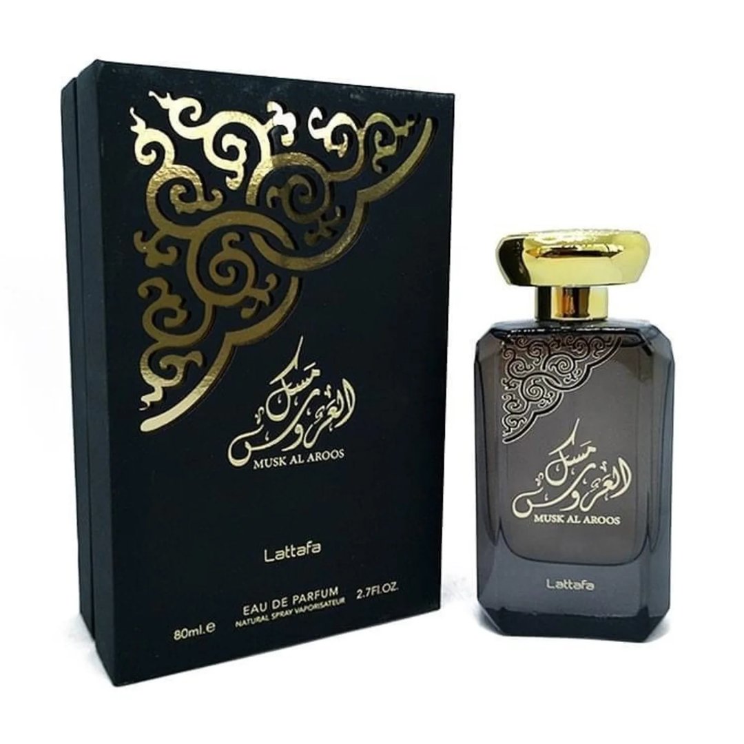 Lattafa Musk Al Aroos by Lattafa 80ml EDP — A black perfume box with gold ornate cutouts and Arabic calligraphy sits next to a dark glass perfume bottle with a gold cap and matching ornate design. | Lattafa Musk Al Aroos by Lattafa 80ml EDP — Kotak minyak wangi hitam dengan potongan berukir emas dan kaligrafi Arab