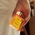 Rayhaan Adonis Icarus Perfume — A gold embossed box sits next to a square amber glass perfume bottle with a gold cap, both featuring intricate embossed patterns. | Rayhaan Adonis Icarus Perfume — Kotak emas bertekstur duduk bersebelahan botol minyak wangi kaca berwarna ambar berbentuk segi empat dengan penutup emas