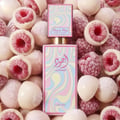 Lattafa Ajwad Pink 2 Pink Creamy Elixir EDP — Pink rectangular bottle with a colorful wavy pattern, topped with a smaller black cap featuring a similar wavy design and gold accents.