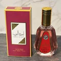 Ard Al Zaafaran Ameerat Al Arab Princess of Arabia 50ml — A red and gold perfume box stands next to a clear glass perfume bottle with a gold cap and a red label. | Ard Al Zaafaran Ameerat Al Arab Princess of Arabia 50ml — Kotak minyak wangi merah dan emas berdiri di sebelah botol minyak wangi kaca jernih dengan