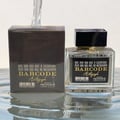 Paris Corner Autograph 100ml — A perfume bottle and its box are displayed side-by-side against a white background. Both feature a barcode design and the text "BARCODE Autograph" in gold lettering. | Paris Corner Autograph 100ml — Sebotol minyak wangi dan kotaknya dipamerkan bersebelahan di atas latar belakang putih.