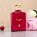 Maison Alhambra Avant Ruby Eau De Parfum 100ml — A bright pink glass perfume bottle with a gold textured cap stands next to its white and gold patterned box, both featuring the Avant Ruby branding and a deer logo. | Maison Alhambra Avant Ruby Eau De Parfum 100ml — Botol kaca berwarna merah jambu terang dengan penutup