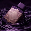 Lattafa Bade'e Al Oud Amethyst Fusion 100ml — A purple perfume bottle with a gold geometric label sits next to its matching box, which has a gold frame and a window showing the bottle inside. | Lattafa Bade'e Al Oud Amethyst Fusion 100ml — Botol minyak wangi ungu dengan label geometri emas duduk bersebelahan dengan