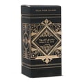 Ard Al Zaafaran Badee Al Oud Eau De Parfum 50ml — Black and gold geometric patterned box next to a clear glass perfume bottle with a gold cap, on a white background. | Ard Al Zaafaran Badee Al Oud Eau De Parfum 50ml — Kotak hitam dan emas bercorak geometri di sebelah botol minyak wangi kaca jernih bertudung emas, di