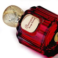 Maison Alhambra Baroque Rouge Extrait 100ml by Maison Alhambra — Red faceted glass perfume bottle with gold cap next to a red and gold ornate box with a bird and deer motif | Maison Alhambra Baroque Rouge Extrait 100ml by Maison Alhambra — Botol kaca merah berfaset dengan penutup emas di sebelah kotak merah dan emas