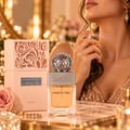 Lattafa Beyond Precious by Lattafa 100ml EDP Women — Clear glass perfume bottle with orange liquid, silver ornate sphere cap, and a peach decorative box with intricate cutouts.