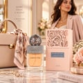 Lattafa Beyond Precious by Lattafa 100ml EDP Women — Clear glass perfume bottle with orange liquid, silver ornate sphere cap, and a peach decorative box with intricate cutouts.