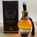 Grandeur Cashmere Luxe 100ml by Grandeur — A faceted glass perfume bottle with a black gem-like cap and a black tassel hanging from the neck, against a white background. | Grandeur Cashmere Luxe 100ml by Grandeur — Botol kaca berfaset dengan penutup seperti permata hitam dan juntai hitam tergantung di lehernya