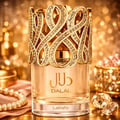 Lattafa Dalal Lattafa 100ml Women — Perfume bottle with ornate gold filigree cap, adorned with rhinestones, next to its white and gold box with matching filigree design.