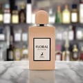Maison Alhambra Floral Bloom — A beige perfume bottle with a peach cap stands next to its matching beige box, both featuring floral and deer motifs. | Maison Alhambra Floral Bloom — Botol minyak wangi berwarna krim dengan penutup pic berdiri di sebelah kotak sepadan berwarna krim, kedua-duanya menampilkan motif bunga