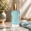 Maison Alhambra Glacier Flora 100ml Maison Alhambra — A blue perfume bottle with a gold cap and vertical gold lines on the glass, stands next to its matching cylindrical blue and gold patterned box on a white background. | Maison Alhambra Glacier Flora 100ml Maison Alhambra — Botol minyak wangi biru dengan penutup