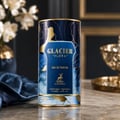 Maison Alhambra Glacier Flora 100ml Maison Alhambra — A blue perfume bottle with a gold cap and vertical gold lines on the glass, stands next to its matching cylindrical blue and gold patterned box on a white background. | Maison Alhambra Glacier Flora 100ml Maison Alhambra — Botol minyak wangi biru dengan penutup