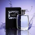 Rasasi Hawas For Him Eau De Parfum 100ml by Rasasi — A clear glass perfume bottle with purple liquid and a textured grey cap sits next to a black product box with a snakeskin pattern label. | Rasasi Hawas For Him Eau De Parfum 100ml by Rasasi — Botol minyak wangi kaca jernih dengan cecair ungu dan penutup kelabu