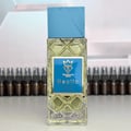 Bujairami Hectic — Clear faceted glass perfume bottle with blue cap next to blue presentation box with gold logo