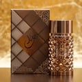Ard Al Zaafaran Jazzab Gold Eau De Parfum 100ml — A gold-toned perfume bottle with a diamond-patterned cage sits next to its matching patterned box on a white background. | Ard Al Zaafaran Jazzab Gold Eau De Parfum 100ml — Botol minyak wangi berwarna emas dengan sangkar bermotif berlian duduk bersebelahan dengan kotak