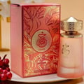 Paris Corner Khair Fusion Her 100ml — Red and gold patterned box next to a frosted pink perfume bottle with a gold textured cap. | Paris Corner Khair Fusion Her 100ml — Kotak corak merah dan emas di sebelah botol minyak wangi merah jambu beku dengan penutup bertekstur emas.