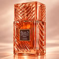 Lattafa Khamrah Mira by Lattafa EDP Unisex — Amber glass perfume bottle with a textured cap, next to its pink and blue watercolor-style box with gold accents.