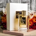 Maison Alhambra Kismet for Women 100ml by Maison Alhambra — A white box and a clear glass perfume bottle with gold accents and a deer emblem, displayed against a white background. | Maison Alhambra Kismet for Women 100ml by Maison Alhambra — Peti putih dan botol minyak wangi kaca jernih dengan perincian emas dan